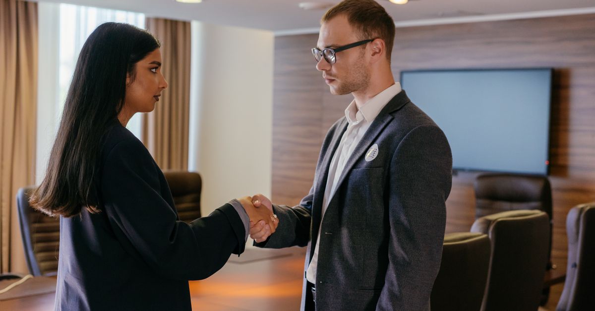 Two professionals shaking hands in a modern conference room, symbolizing successful business agreement.