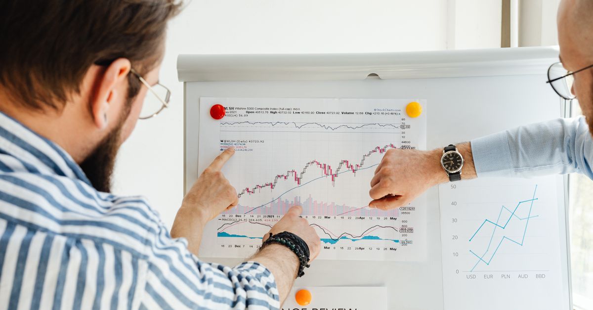 Colleagues discussing data trends on a whiteboard with graphs and charts.