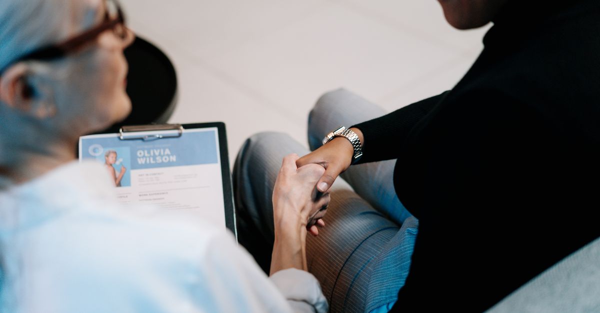 Two professional women having a handshake in an office setting, focusing on recruitment and connection.
