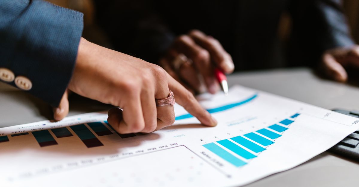 Close-up of hands analyzing financial charts during a business meeting.