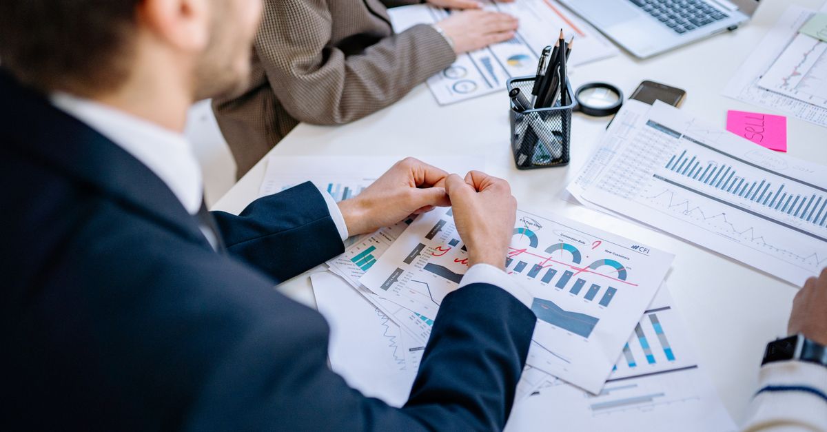Business team analyzing financial graphs at a meeting table, fostering collaboration in an office environment.